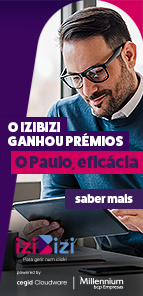 Rapaz sentado à secretária com os pés em cima da mesma e com um tablet na mão